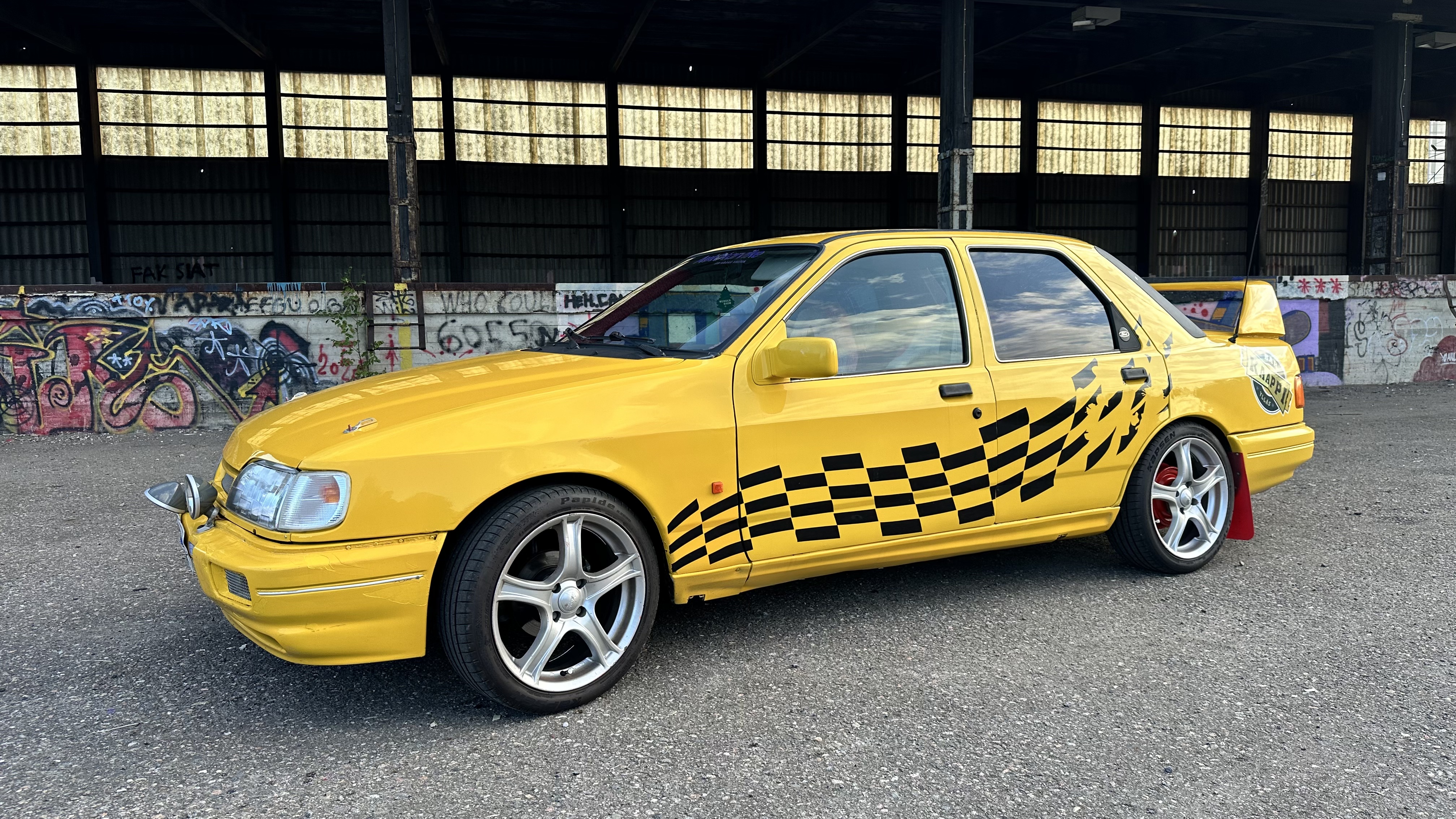 Keltainen Ford Sierra TIS-51 sivusta kuvattuna, kyljessä ruutulippukuvio